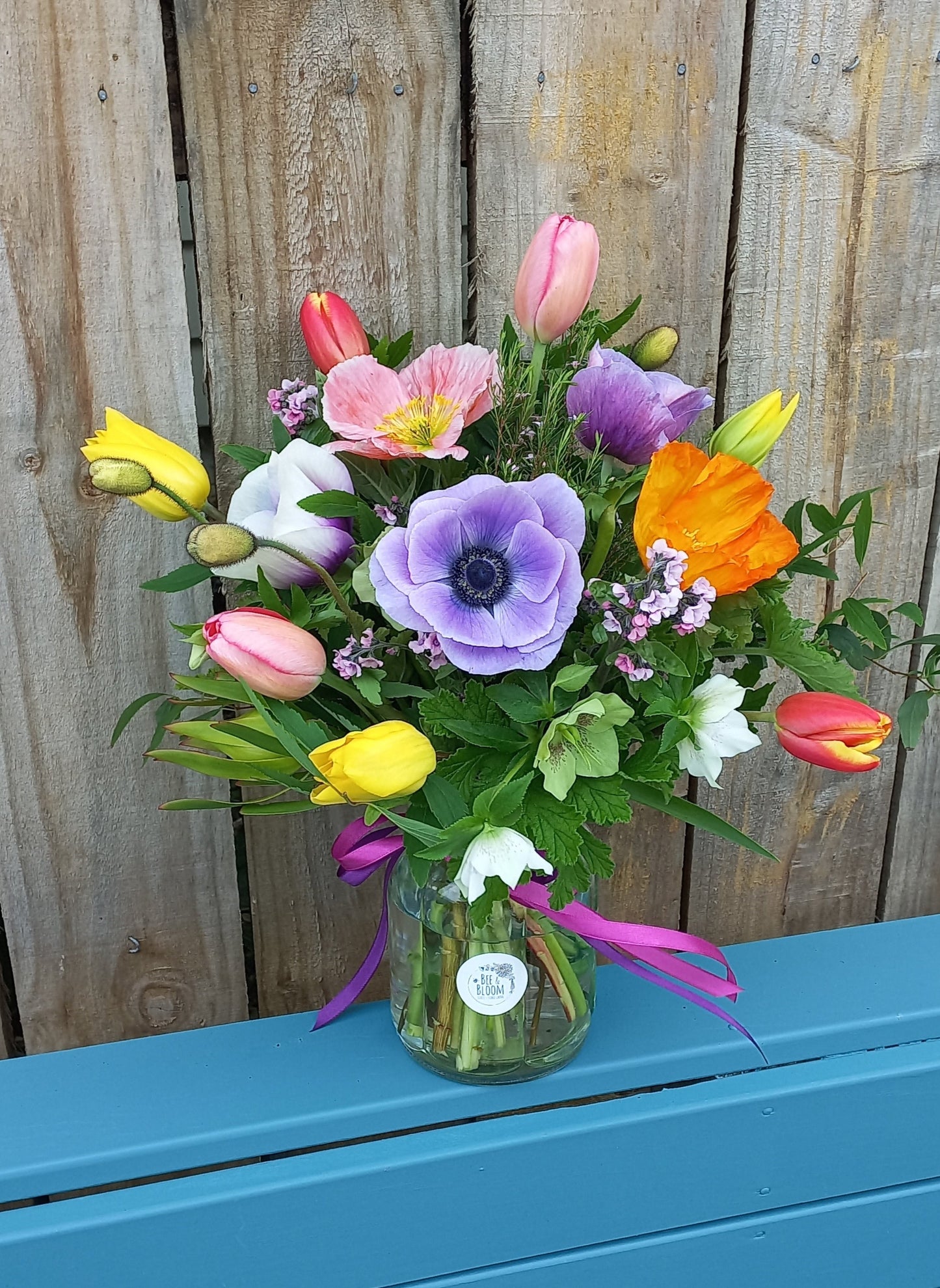 Bouquet of colorful flowers on a wooden surface with a blue background