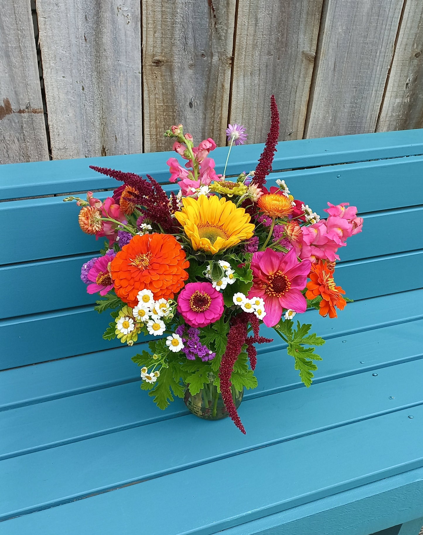 Colorful bouquet of flowers on a blue chair against a wooden background
