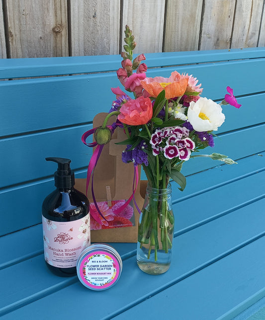 Bouquet of flowers and a bottle on a blue surface next to wooden planks.