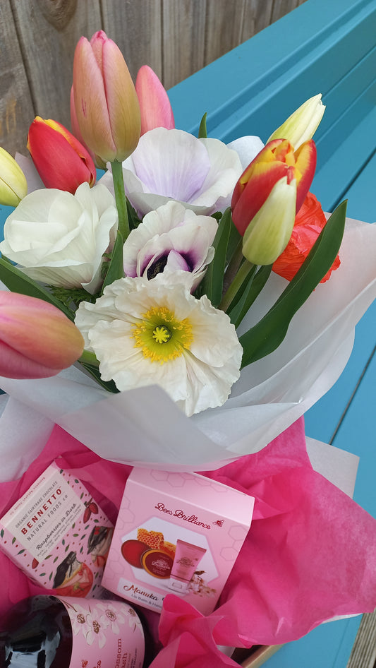 Bouquet of flowers with a pink gift box on a wooden surface.