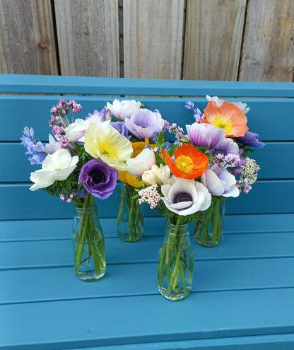 Colorful flowers arranged on green bottles against a blue wooden background