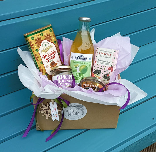 Gift basket with a bottle of juice on a blue bench outdoors.
