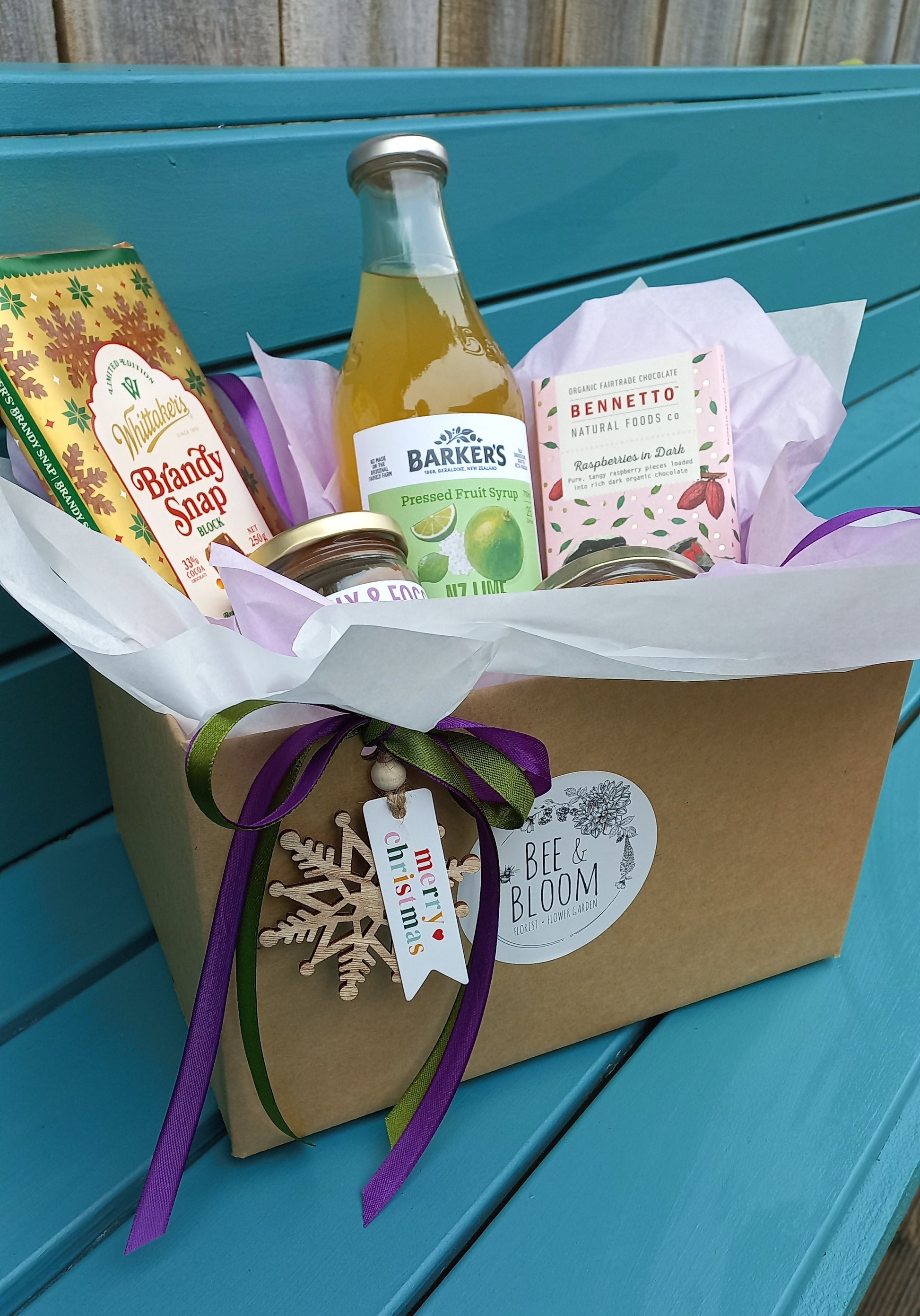 Gift set with bottles and a bouquet on a teal surface