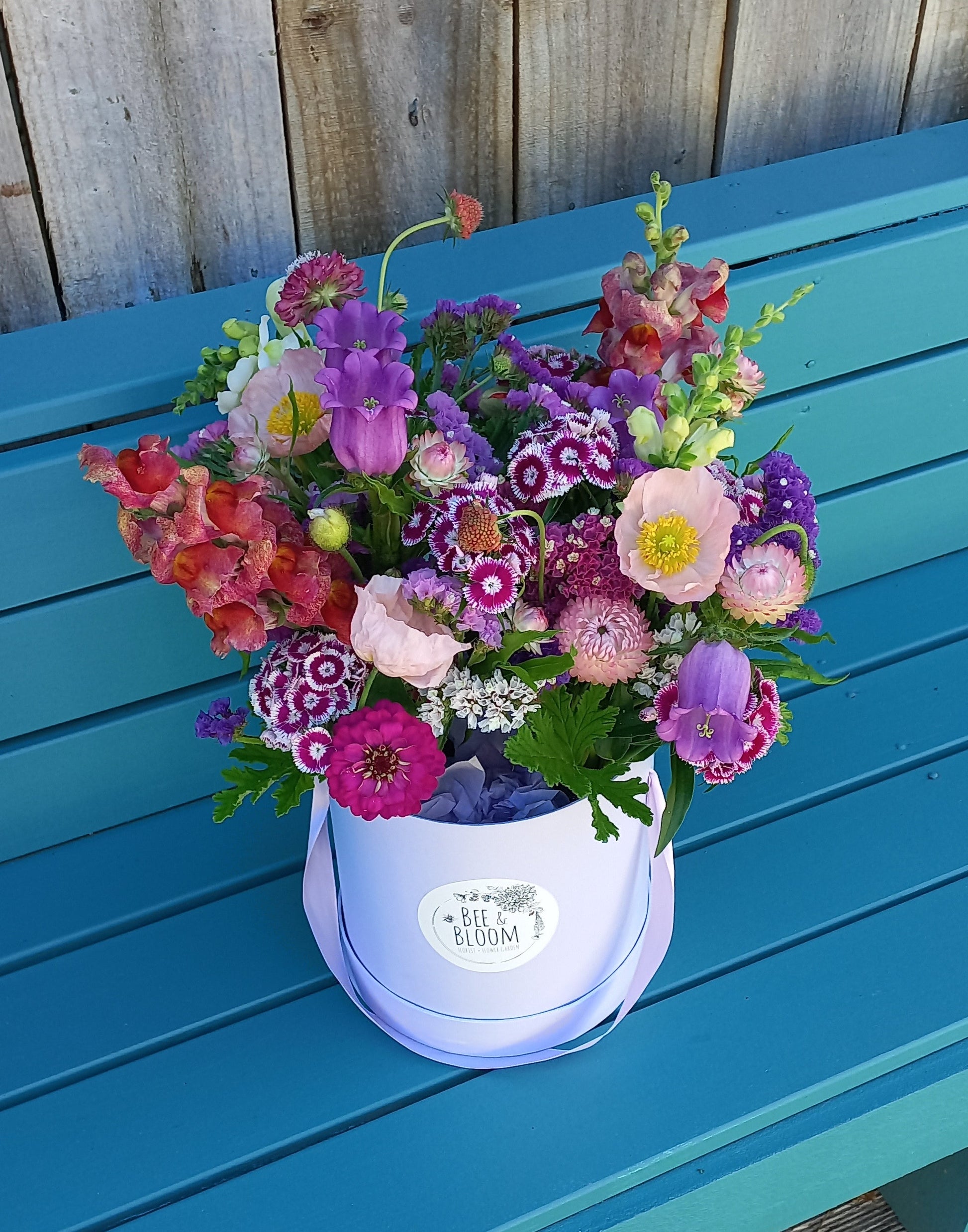 Colorful bouquet of flowers on a blue chair with a wooden floor background