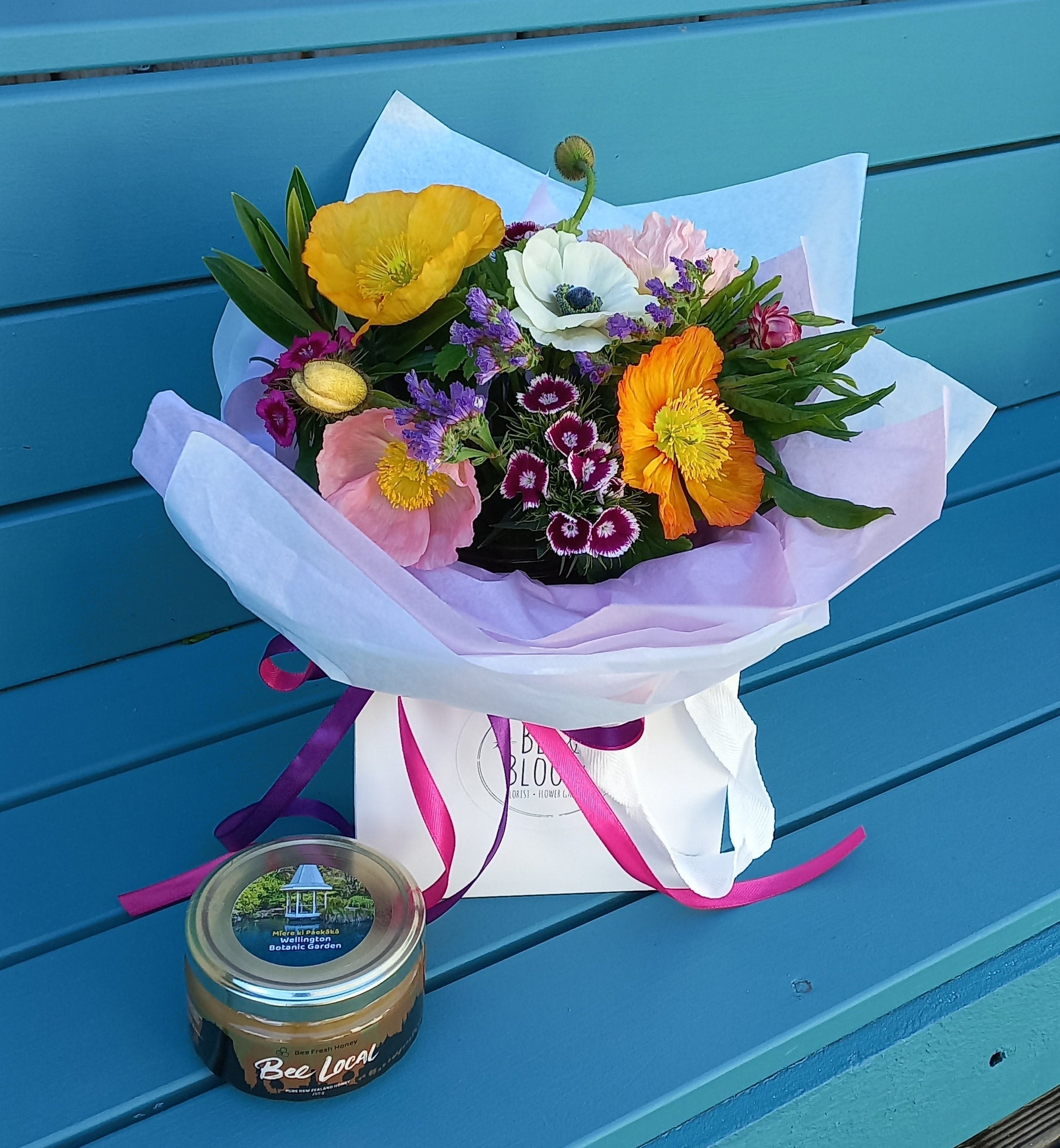 Bouquet of flowers and a jar on a blue wooden surface