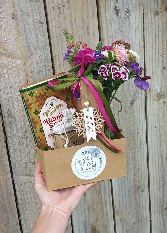 Hand holding a gift box with flowers on a wooden surface