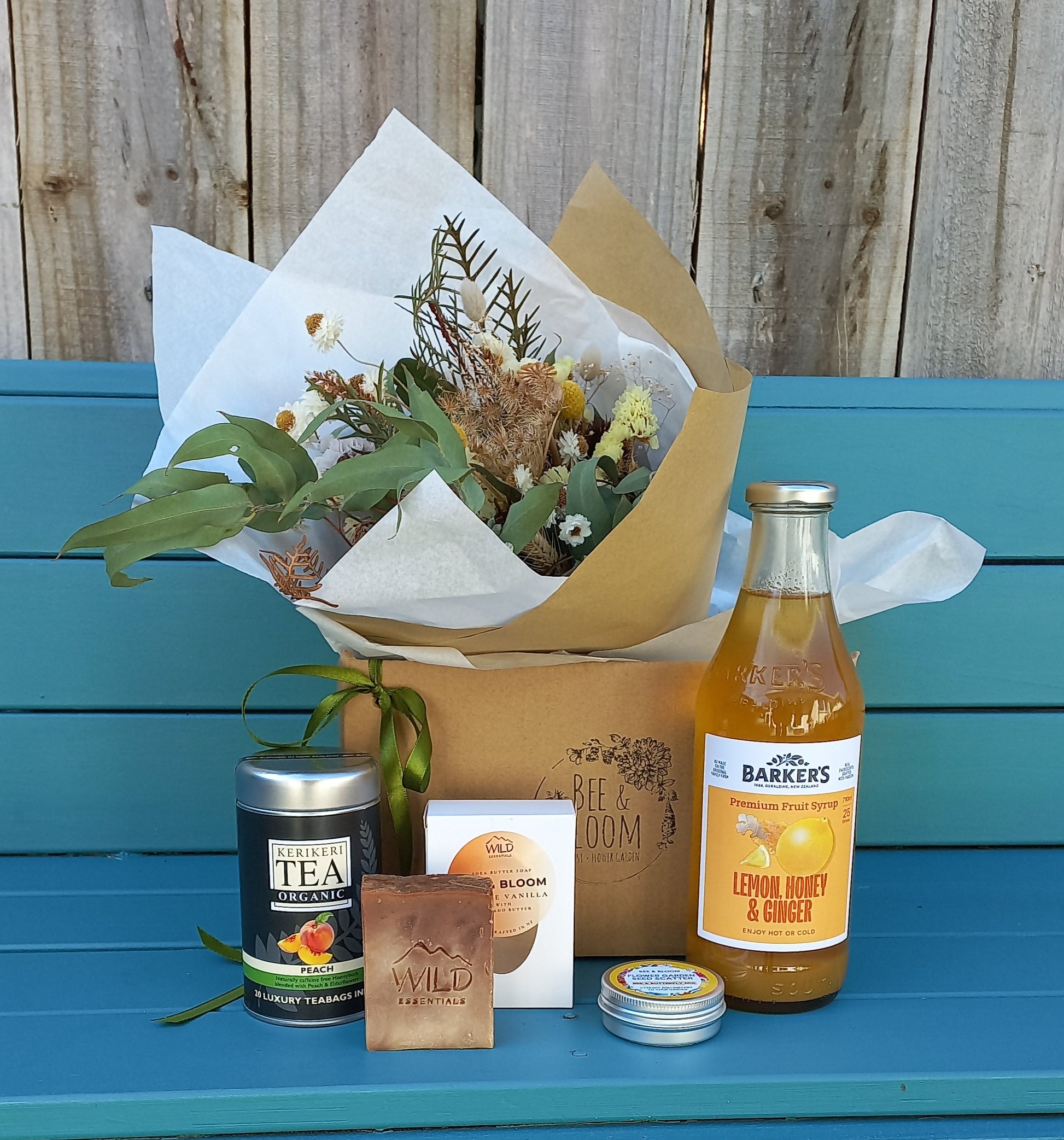 Bouquet, bottles, and a box on a teal surface with wooden background